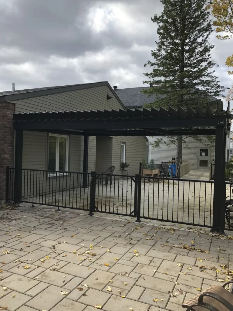 Pergola adossée au bâtiment derrière la clôture, Manoir Soleil à Chambly