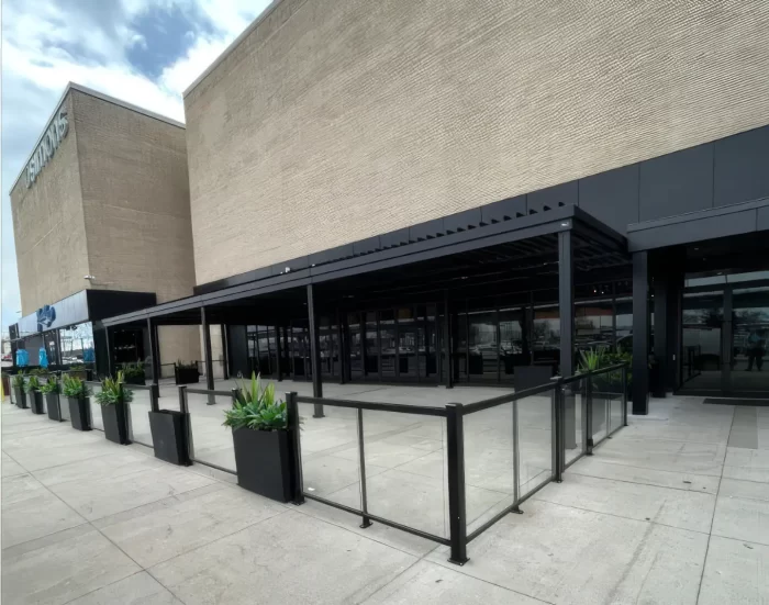 Pergola noire au-dessus de la terrasse vitrée longeant le centre commercial, Milestones à Pointe-Claire