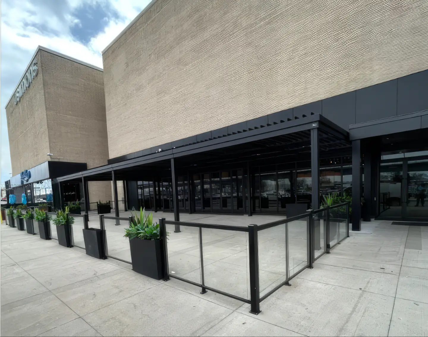 Pergola noire au-dessus de la terrasse vitrée longeant le centre commercial, Milestones à Pointe-Claire