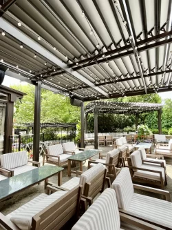 Fauteuils rembourrés sous une pergola noire à lames intégrées, Miller Tavern à Toronto