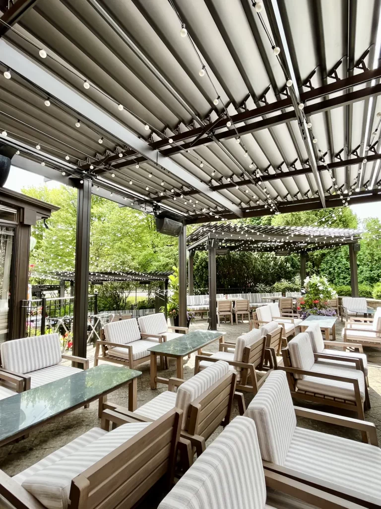 Fauteuils rembourrés sous une pergola noire à lames intégrées, Miller Tavern à Toronto