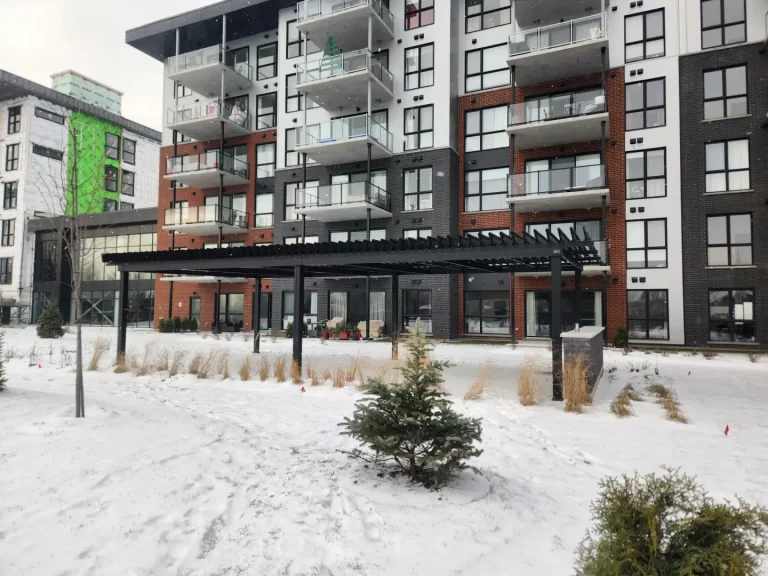 Pergola courant le long de la façade enneigée, Projet Citiluxx à Saint-Hubert