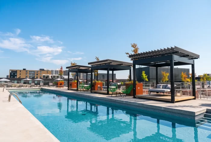 Piscine de toit bordée de pergolas sombres et de salons, Quartier Général Condos à Montréal