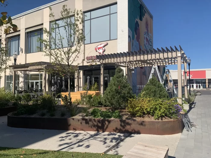 Pergola running along the building and its planters, Que Sera Syrah in Brossard