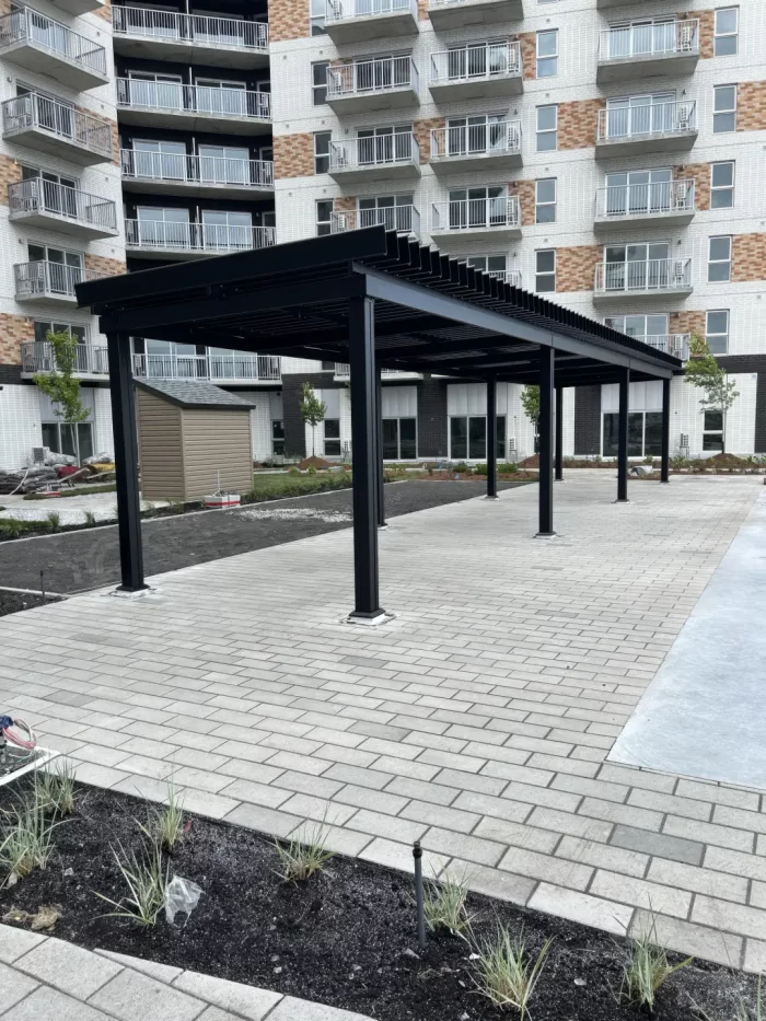 Pergola noire au-dessus de l'allée pavée de l'immeuble, Cibèle à Saint-Hyacinthe
