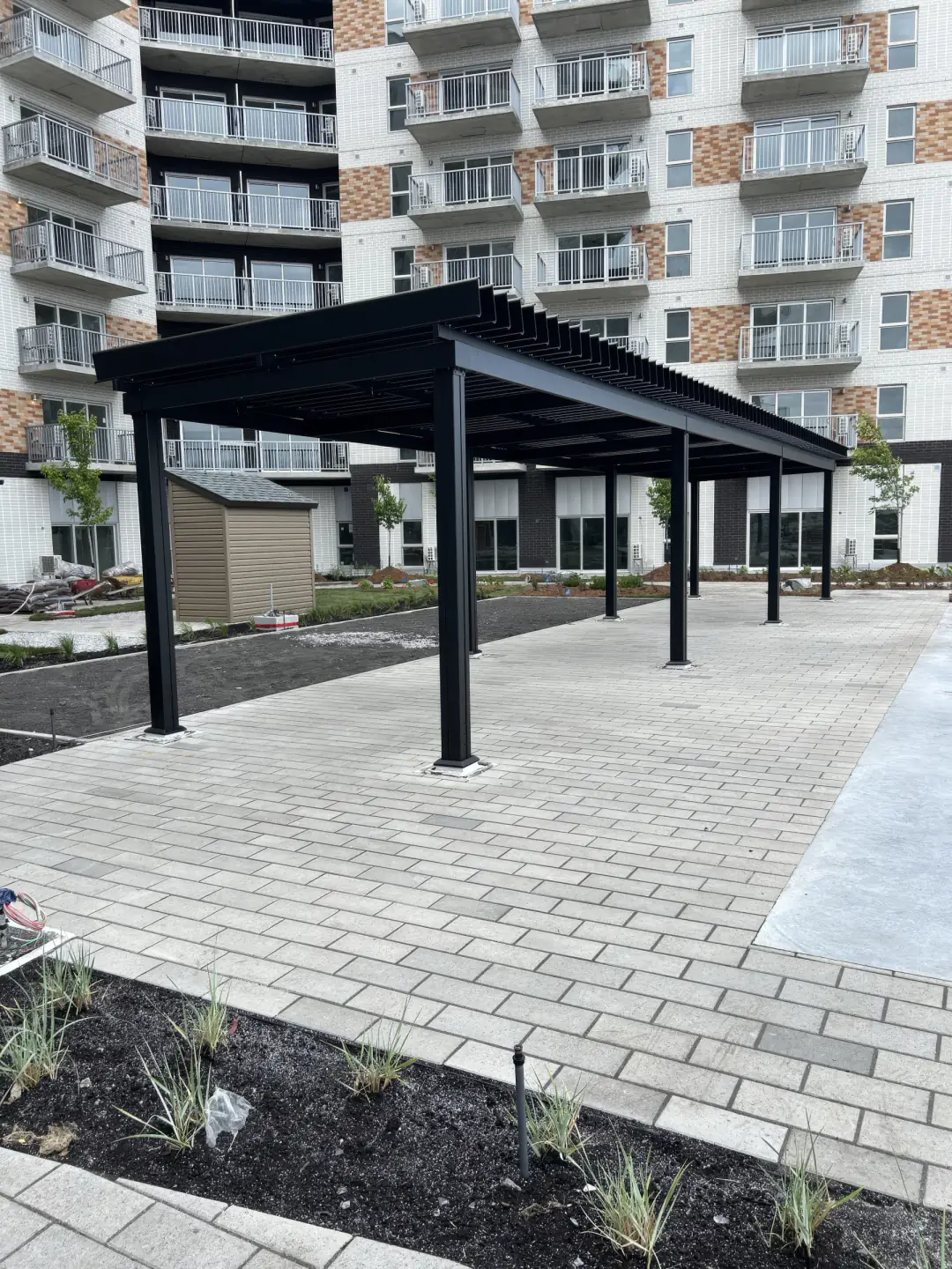 Pergola noire au-dessus de l'allée pavée de l'immeuble, Cibèle à Saint-Hyacinthe