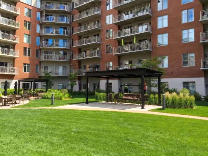 Pergola sombre sur la pelouse devant la résidence de brique, Résidence Place Belvédère à Trois-Rivières
