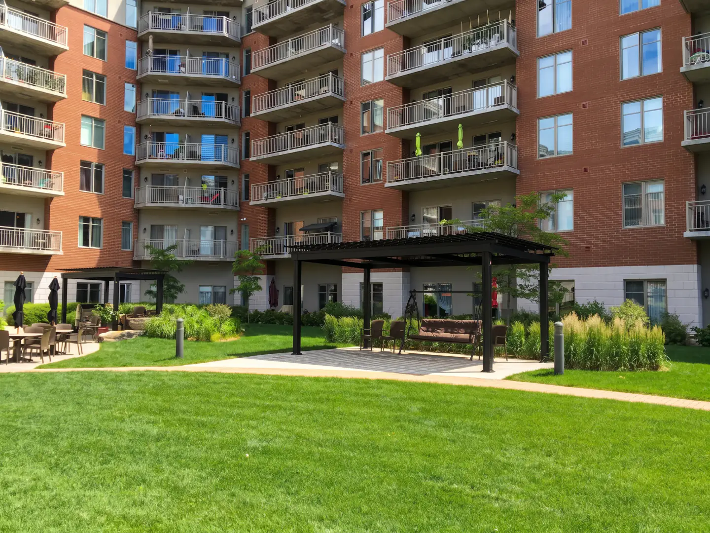 Pergola sombre sur la pelouse devant la résidence de brique, Résidence Place Belvédère à Trois-Rivières