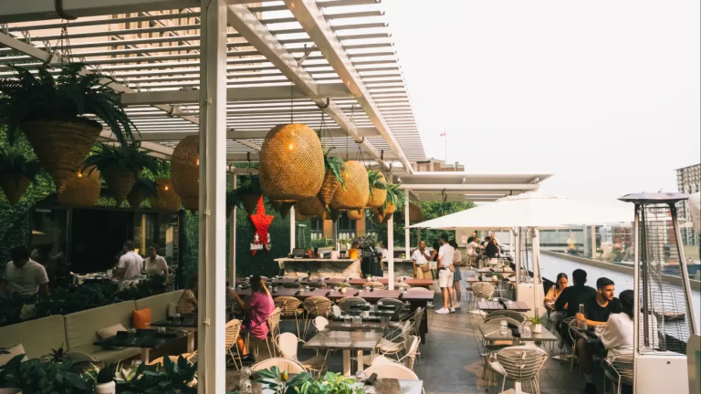 Guests seated under the white pergola and its woven pendants, Restaurant Belvu in Montréal