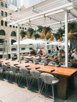 Long communal tables and parasols under the white pergola, Restaurant Belvu in Montréal