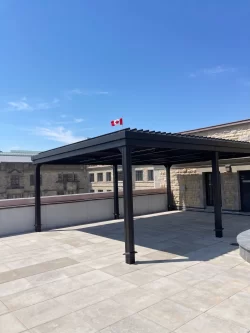 Dark pergola on the stone terrace beneath the flag, Royal Canadian Mint in Ottawa