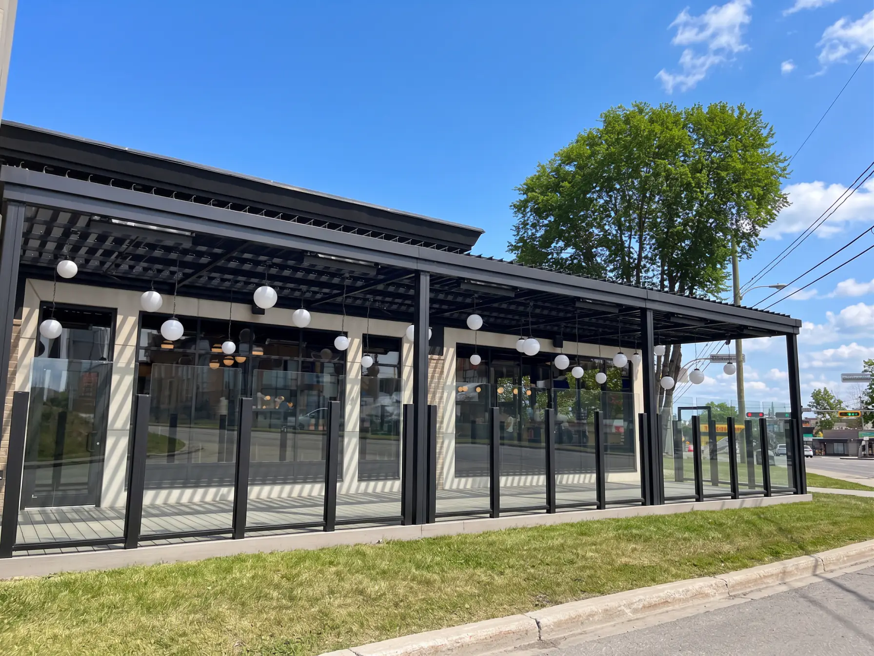 Pergola noire au-dessus de la terrasse vitrée et ses luminaires ronds, Les Rôtisseries St-Hubert à Saint-Jérôme