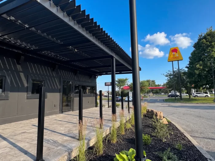 Pergola noire longeant le restaurant sous l'enseigne, Les Rôtisseries St-Hubert à Sainte-Julie