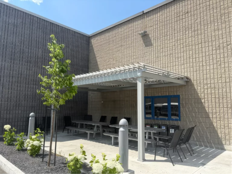 Cour et tables abritées par la pergola blanche, Société de transport de Sherbrooke