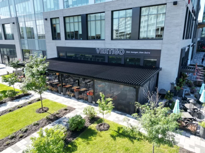 Pergola noire longeant la terrasse et ses aménagements paysagers, Restaurant Vertigo à Brossard