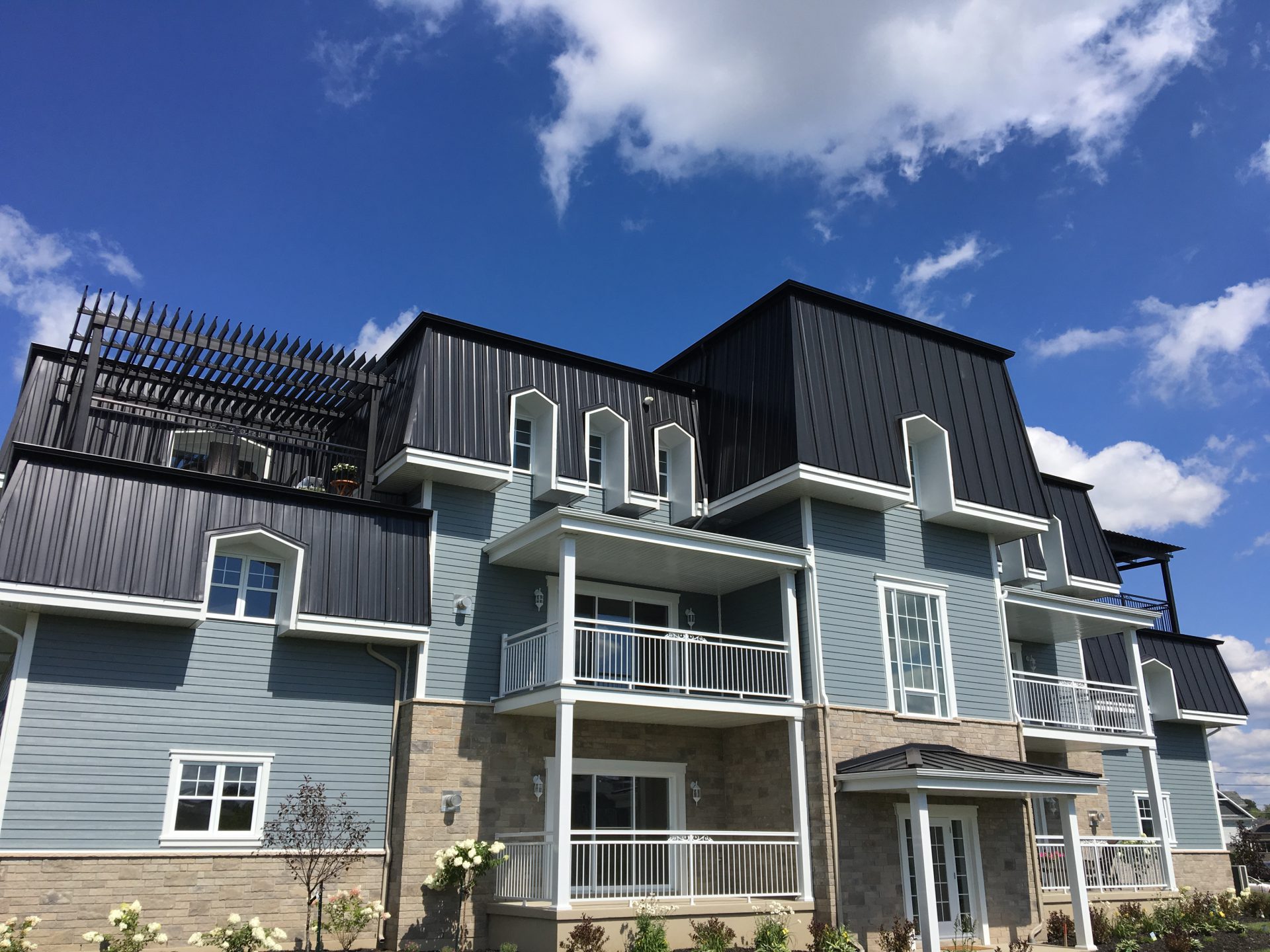 Pergola sombre sur le toit d'un immeuble bleu-gris, Les Victoriennes à Bromont